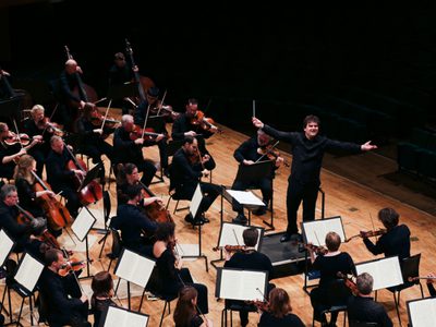 Gi J WNO Orchestra 105 Bird's eye view of the orchestra, with the conductor's arms out wide.