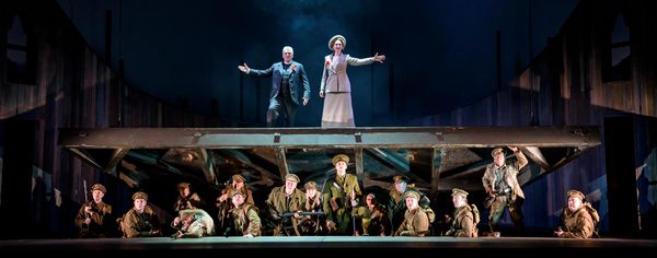 WNO In Parenthesis Peter Coleman Wright Bard Of Britannia Alexandra Deshorties Bard Of Germania And Company Photo Credit Bill Cooper 942 Bill Cooper The Bard Of Britannia and Bard Of Germania stand above soldiers, who are crouching on the ground.