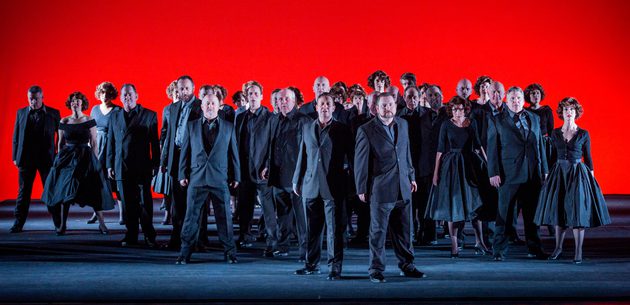 WNO Chorus WNO Chorus Photo Credit Robert Workman 041 Robert Workman Men and women from the WNO Chorus dressed in grey, with a bright red background.