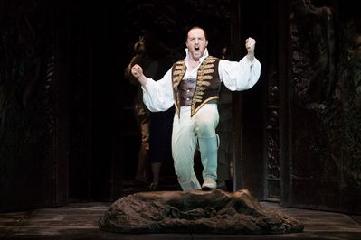 WNO Don Giovanni Gavan Ring Don Giovanni Photo Credit Richard Hubert Smith 1369 Richard Hubert-Smith 2018 Man in uniform sings with fists in the air and foot resting on bag on the floor.