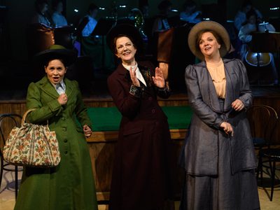 WNO Rhondda Rips It Up! Catherine Wood Lottie Rosie Hay Sybil And Madeleine Shaw Lady Rhondda Photo Credit © Jane Hobson 2705 Jane Hobson 2018 Lottie, Sybil and Lady Rhondda appear jolly, singing to the audience, with the orchestra in the background.