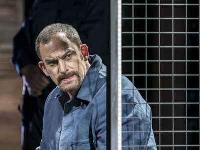 WNO Dead Man Walking Morgan Smith Joseph De Rocher Photo credit Johan Persson 01111 Johan Persson 2019 Man sat behind wire fence looks pensive.