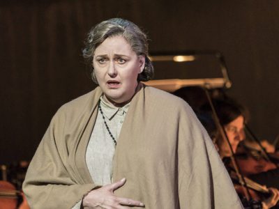 WNO The Consul Catherin Wyn Rogers The Mother Photo credit Johan Persson 1264 Johan Persson 2019 Woman with shawl wrapped around her looking worried.