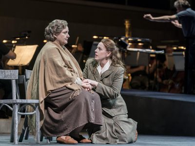 WNO The Consul Catherine Wyn Rogers The Mother Giselle Allen Madga Sorel Photo credit Johan Persson 1093 Johan Persson 2019 Woman sat on chair, other woman kneeling at her feet holding her hands.