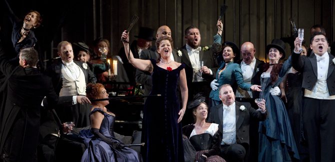 WNO La traviata Rebecca Afonwy Jones Flora Linda Richardson Violetta Kang Wang Alfredo and WNO Chorus Photo credit Betina Skovbro 2941 Betina Skovbro A crowd are cheering, arms raised.