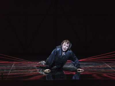 WNO Roberto Devereux Barry Banks Roberto Devereux Photo credit Bill Cooper 0379 Bill Cooper 2019 Man on the floor raised on his hands red thread coming off him.