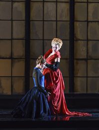 WNO Roberto Devereux Justina Gringytė Sara Joyce El Khoury Elisabetta Photo credit Bill Cooper 0037 Bill Cooper 2019 Woman kneels in front of standing woman who looks smug.