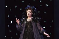 WNO The Magic Flute Anna Siminska Queen of the Night Photo credit Bill Cooper 0603 Bill Cooper 2019 Woman dressed in black with feathered collar sings with one hand in the air.