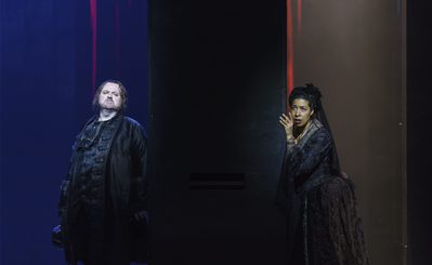 WNO Un ballo in maschera Gwyn Hughes Jones Riccardo Mary Elizabeth Williams Amelia Photo credit Bill Cooper© 0201 Bill Cooper 2019 Woman leans against wall looking worried, other side of wall a man looks towards her pensive.