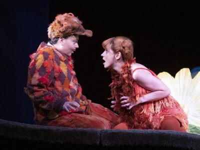 Aoife Miskelly as Vixen Lucia Cervoni as Fox The Cunning Little Vixen Photocredit Richard Hubert Smith 4448 Richard Hubert-Smith 2019 Two characters dressed like foxes knelt facing each other excitedly.