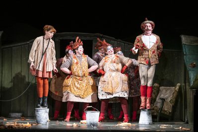 Aoife Miskelly as Vixen Michael Clifton Thompson Cockerel The Cunning Little Vixen Photocredit Richard Hubert Smith 9527 Richard Hubert-Smith 2019 Tied up fox character standing on bucket, hen characters in the middle, cockerel character stood on bucket.