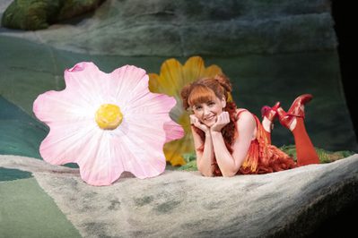 Aoife Miskelly as Vixen The Cunning Little Vixen Photocredit Richard Hubert Smith 4416 Richard Hubert-Smith 2019 Young woman lying next to big flowers with chin in hands.