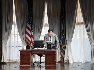 WNO Rigoletto 2019 David Junghoon Kim The Duke Photcredit Richard Hubert Smith 3774 Richard Hubert-Smith 2019 Man leaning on a desk in oval office setting.