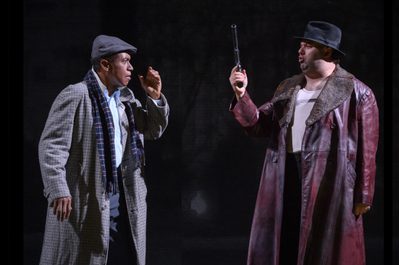 WNO Rigoletto 2019 Mark S Doss Rigoletto and James Platt Sparafucile Photocredit Richard Hubert Smith 7237 Richard Hubert-Smith 2019 Two men converse dark background, one man holds a gun.
