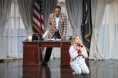 WNO Rigoletto 2019 Mark S Doss Rigoletto and Marina Monzo Gilda Photocredit Richard Hubert Smith 3954 Richard Hubert-Smith 2019 Woman in pyjamas kneel on floor of oval office, behind her a man angrily leans on desk.