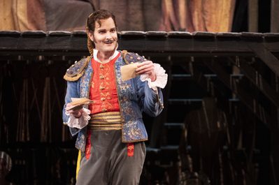 WNO The Barber of Seville Nicholas Lester Figaro photot credit Richa Figaro stood holding papers in hands