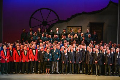 blazeofglorydresskirstenmcternan699 A collection of Male Voice Choirs stand on the stage of a production