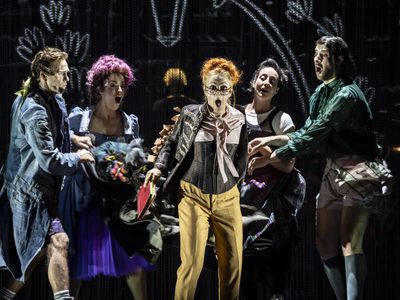 WNO Candide Ed Lyon Candide Claudia Boyle Cunégonde Gillian Bevan Pangloss Francesca Saracino Paquette Mark Nathan Maximilian photo credit Johan Persson 00917 a group take the coat off a woman, revealing their true identity