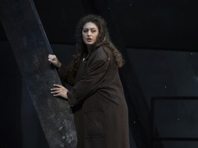 WNO La bohème Anush Hovhannisyan Mimi photo credit Richard Hubert Smith 9155 A woman in a brown coat, hiding behind a steel beam