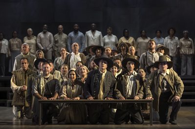 WNO Migrations The Mayflower WNO Chorus photo credit Craig Fuller 2 Group of people, kneeling before a bench, praying in 17th century clothes