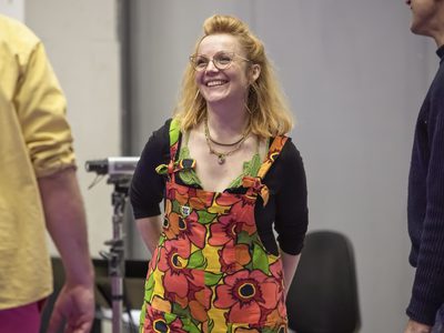 WNO The Magic Flute Daisy Evans Director photo credit Craig Fuller 5660 A women in a pair of floral dungarees smiles at a member of her cast