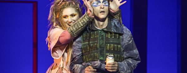 WNO The Magic Flute Jenny Stafford Papagena Quirijn de Lang Papageno photo credit Craig Fuller 4961 A man in hunting equipment stands shocked whilst a women in a pink dress takes her hands from in front of his eyes