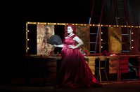 WNO The Makropulos Affair Ángeles Blancas Gulin Emilia Marty photo credit Richard Hubert Smith 8101 Woman in red dress stands before dressing mirrors and lights