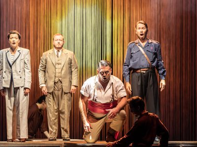 Hanna Hipp as Federico García Lorca Gareth Dafydd Morris as Torero Alun Rhys Jenkins as Maestro Jasey Hall as José Tripaldi Credit Johan Persson 12961 4 people in a line against a bright orange background, one of them is kneeling