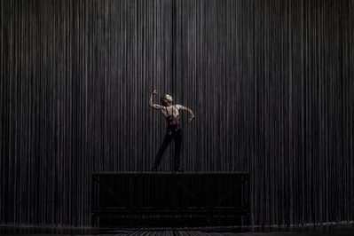 Isaac Tover as Bullfighter Dancer in WNO Ainadamar 2023 Credit Johan Persson 00315 a flamenco dancer stands on a platform in the middle of a ring of hanging chains