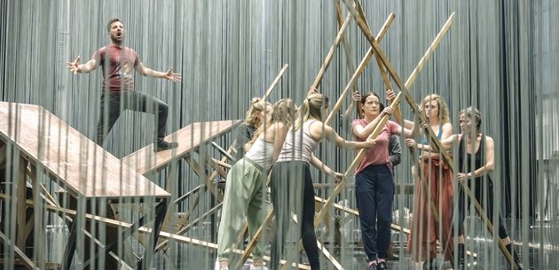 WNO Ainadamar Hanna Hipp Federico García Lorca cast of Ainadamar photo credit Craig Fuller 4975 a group of performers arrange beams of wood into a triangular tunnel, as a man stands on two tables