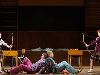 WNO Così fan tutte Sophie Bevan Fiordiligi James Atkinson Guglielmo Egor Zhuravskii Ferrando Kayleigh Decker Dorabella photo credit Elliott Franks 3617 A production shot of two school girls pointing bow and arrows at two men lying on the floor back to back