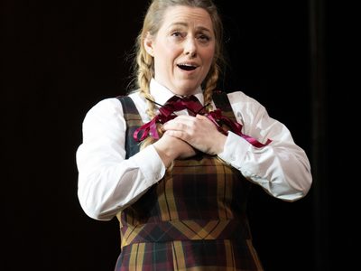 WNO Così fan tutte Sophie Bevan Fiordiligi photo credit Elliott Franks 518 A production shot of a school girl singing with her hands over her heart
