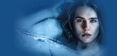 WNO CL1881 S24 Website image 1000x486 Cover Death in Venice A man with long hair looks at the character as he lies back with his arm next to his head against a blue background