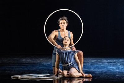 WNO Death in Venice Riccardo Frederico Saggese Jaschiu Selma Hellmann Daughter 2 photo credit Johan Persson 03122 A production shot showing a man and woman looking through a gymnastics hoop