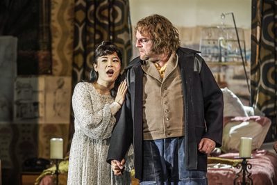 WNO Gianni Schicchi Haegee Lee Lauretta Roland Wood Gianni Photo Credit Craig Fuller IMG 6537 A production shot from Gianni Schicchi showing Lauretta in a white singing whilst holding her father, Gianni Schicchi's arm