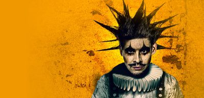 CL2189 A24 Web image 1000x486 Cover Rigoletto A vibrant image of a joker (Rigoletto) with spiked hair and clown makeup and clothing against a vibrant yellow background