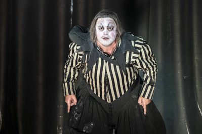 WNO Rigoletto Daniel Luis de Vincente Rigoletto photo credit Richard Hubert Smith 3972 A production shot from Rigoletto. A man (Rigoletto) looks intensely forwards with a white painted face and striped black and white shirt.