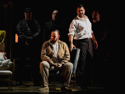 WNO Tosca Andrés Presno Cavaradossi Dario Solari Scarpia Photo Credit Dafydd Owen 1152 Cavaradossi sits on a velvet chair, staring angrily to his right. Scarpia, dressed formally, stands to his left, his hand upon the chair and a sinister expression on his face. His three henchmen stand behind.