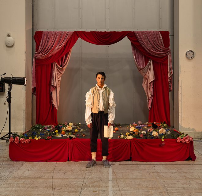 WNO 2627 Launch AL Homepage A man stands in front of a red stage covered in flowers. He's holding a white piece of paper.
