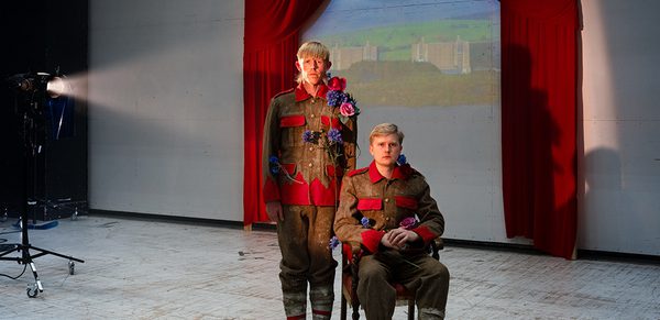 WNO 2627 Launch HW Cover Two men dressed in army gear and flowers stand in front of a projected image of Trawsmynydd Nuclear Station.
