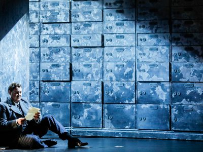 Bruce Sledge Lorenzo Wnos The Merchant Of Venice Photo Credit Johan Persson 826 Johan Persson Lorenzo sits with his back against a wall, reading a document.